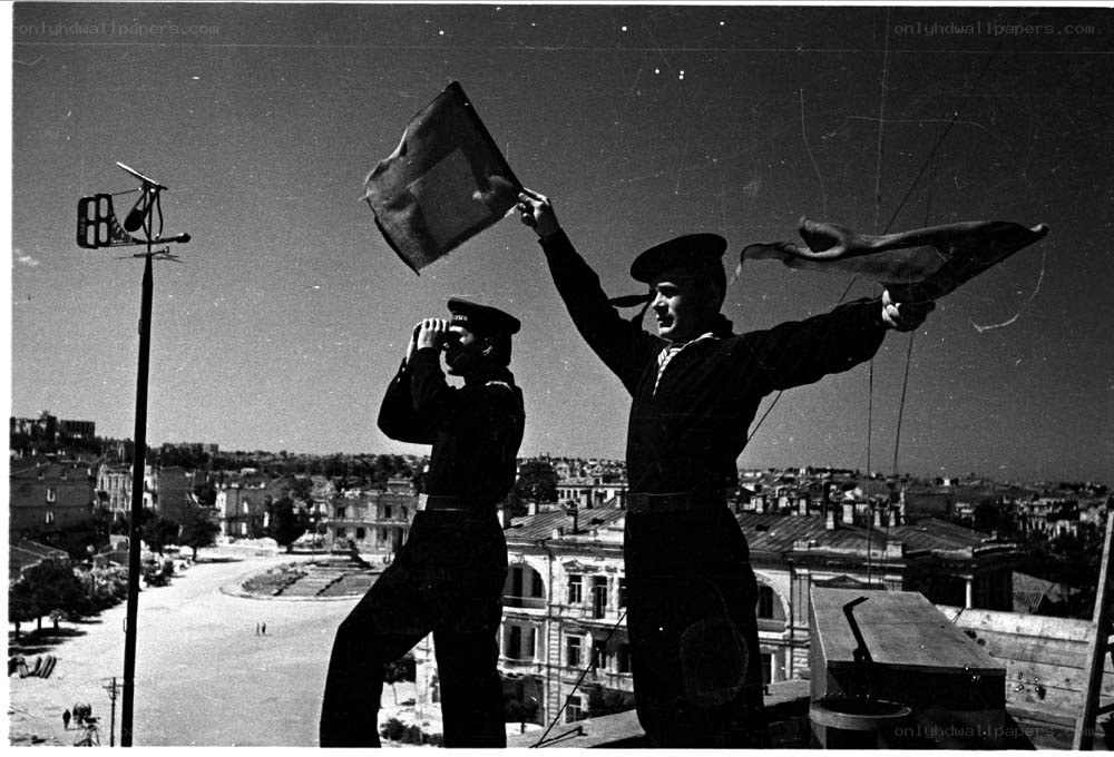 Sailors on a rooftop with flags