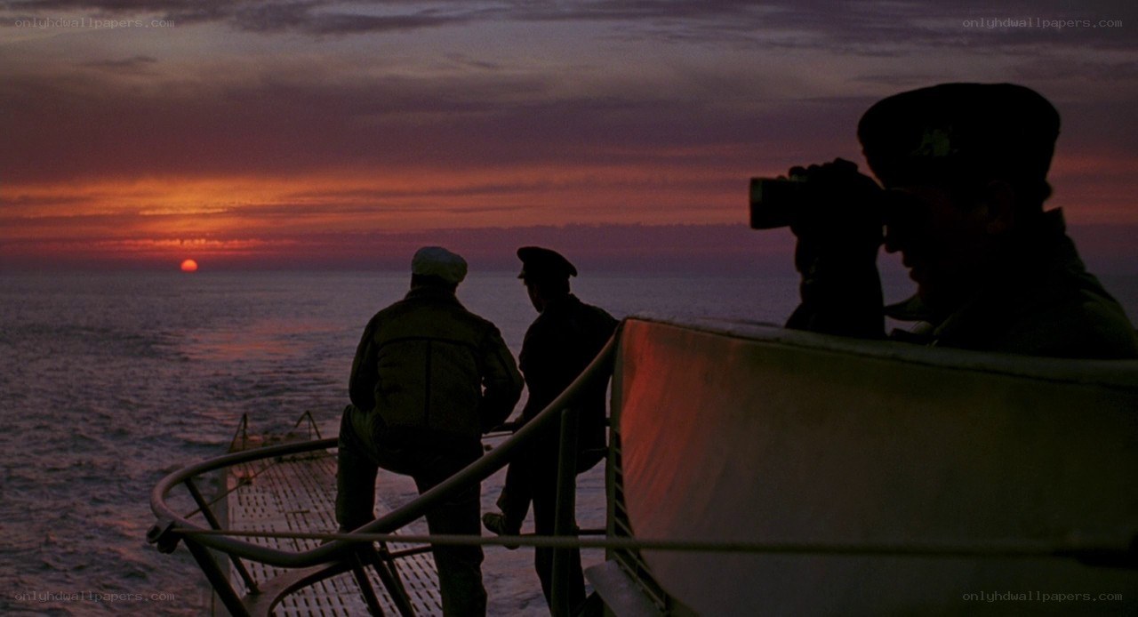 Sailors watch sunset from ship