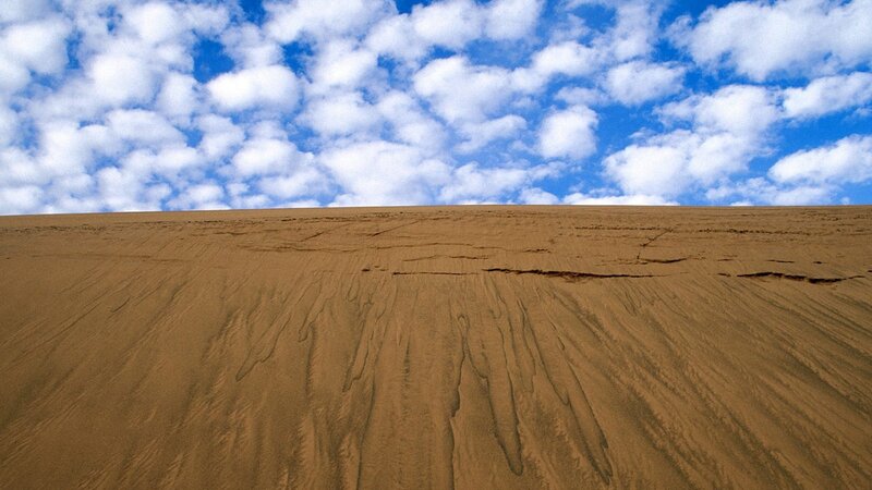 sand dune under cloudy sky
