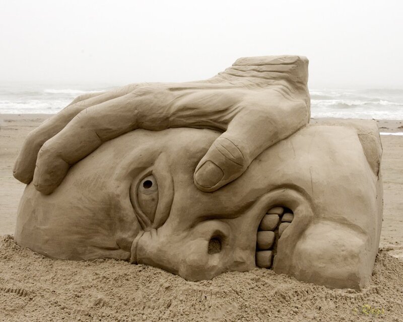 Sand sculpture of face and hand
