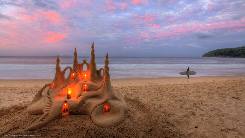Sandcastle at sunset with surfer