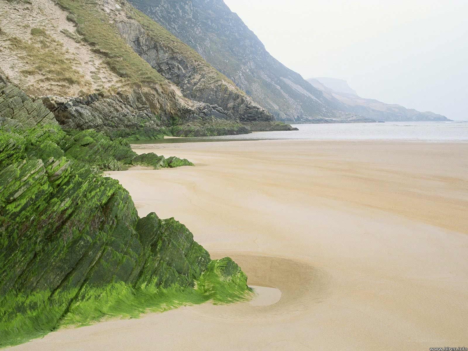 sandy beach with green rocks
