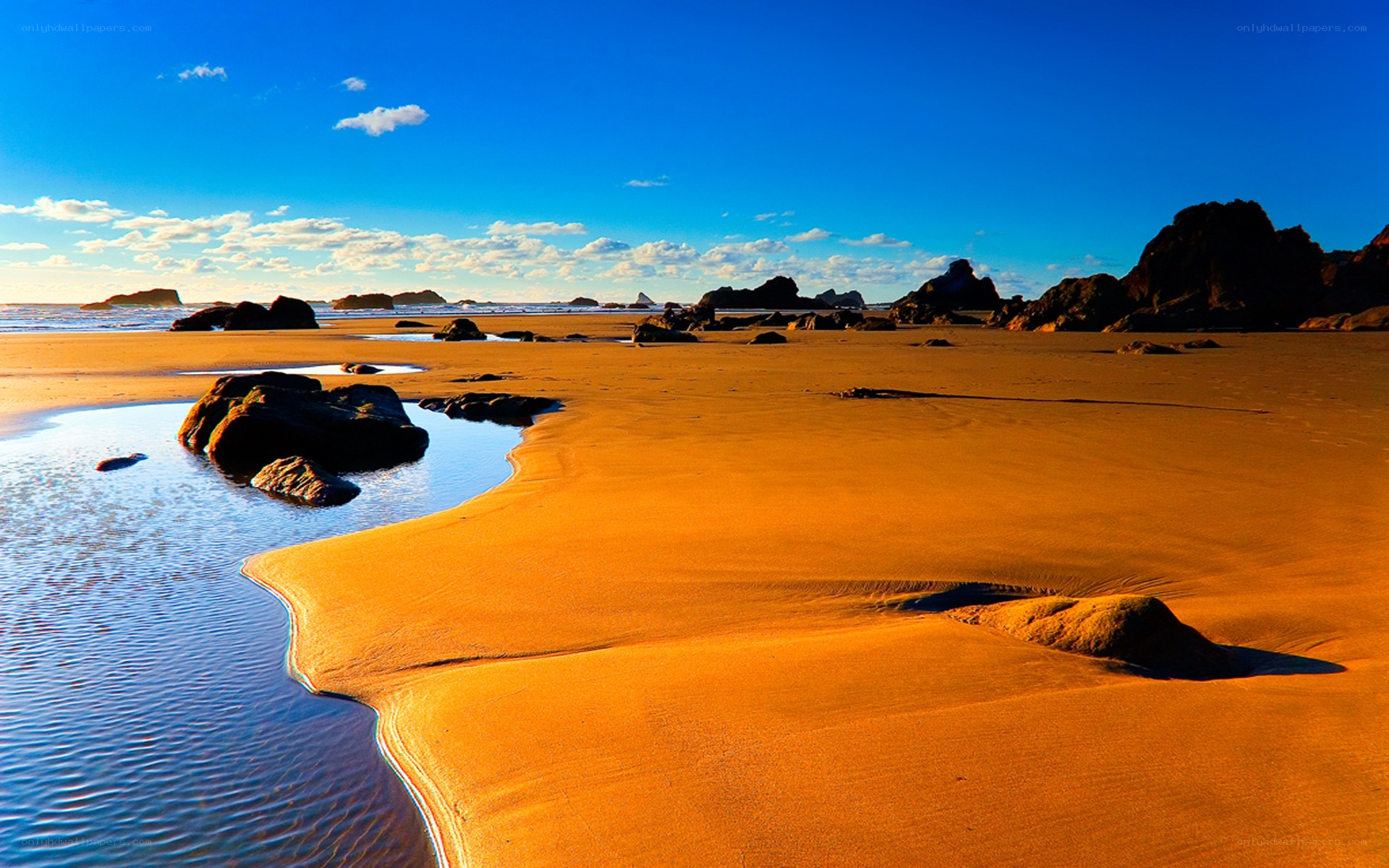 sandy beach with rocks and blue sky