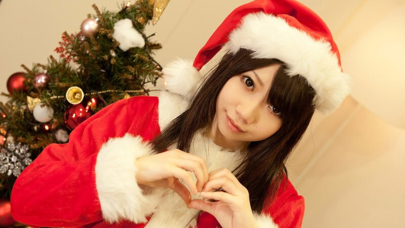 Santa-clad woman making heart gesture