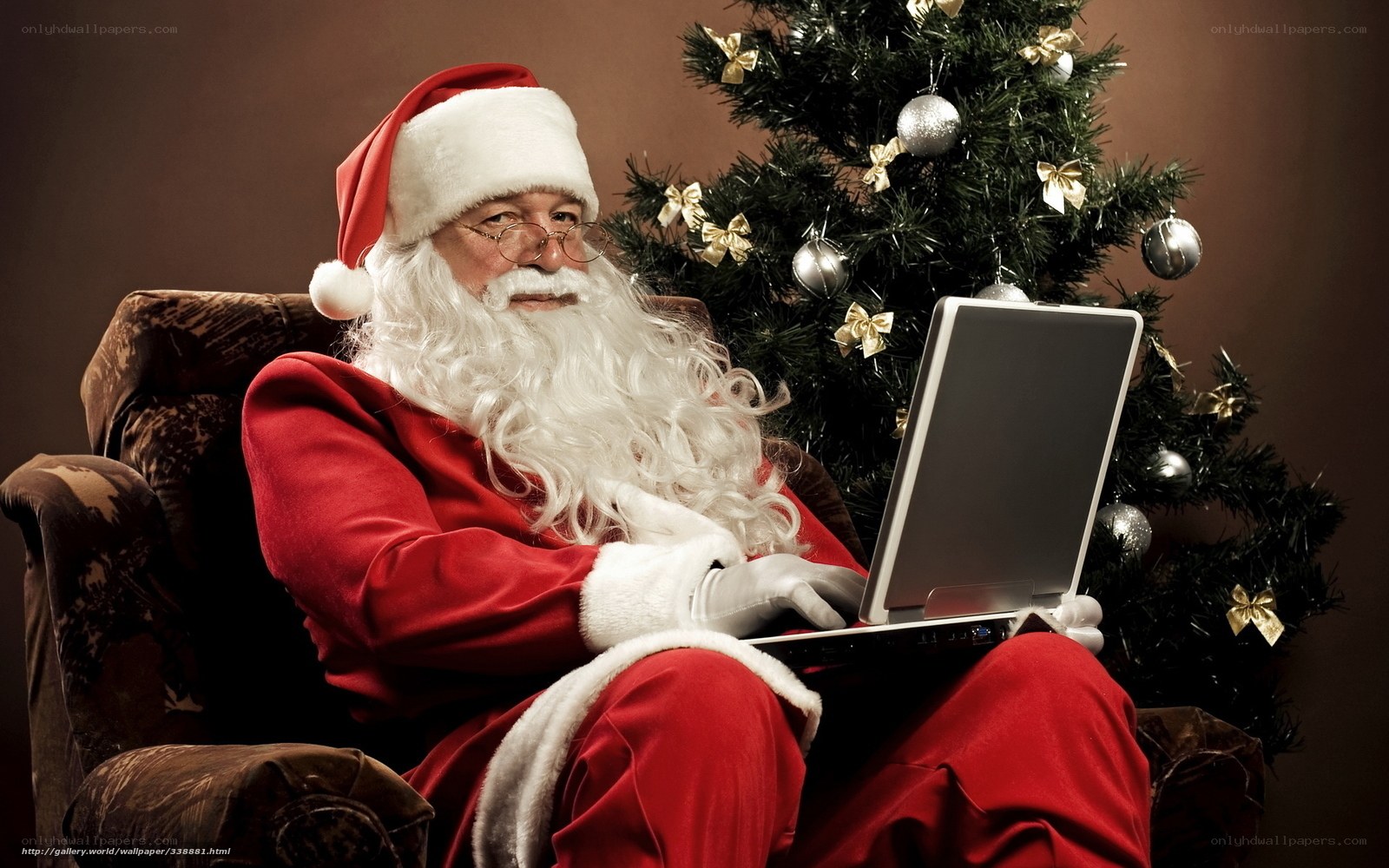 Santa using laptop by Christmas tree