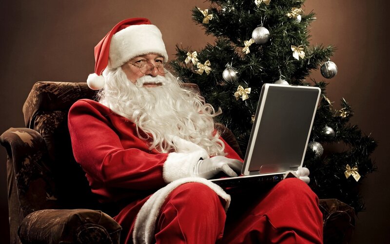 Santa using laptop by tree