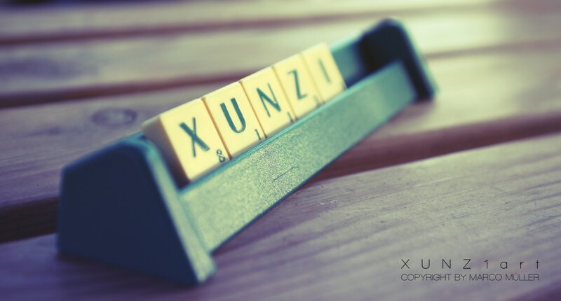 Scrabble tiles spelling XUNZI on a wooden surface