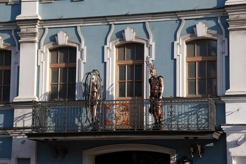 Sculptures on a blue building balcony