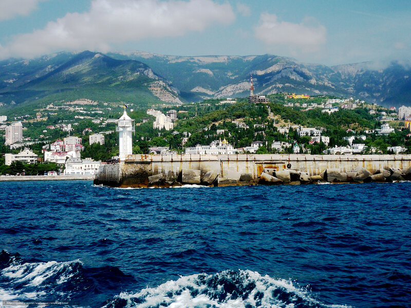 Seaside town with lighthouse and mountains