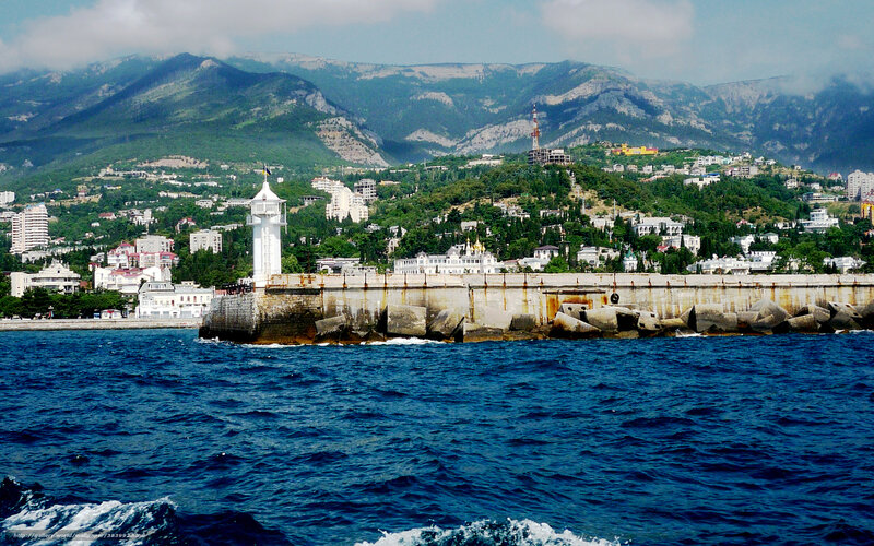 Seaside town with lighthouse and mountains