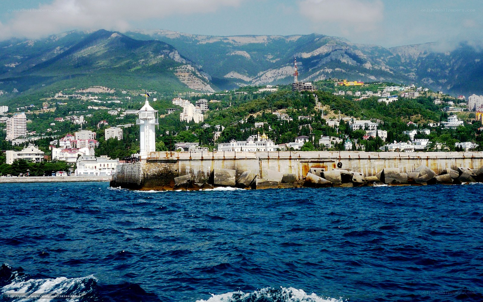 Seaside town with lighthouse and mountains