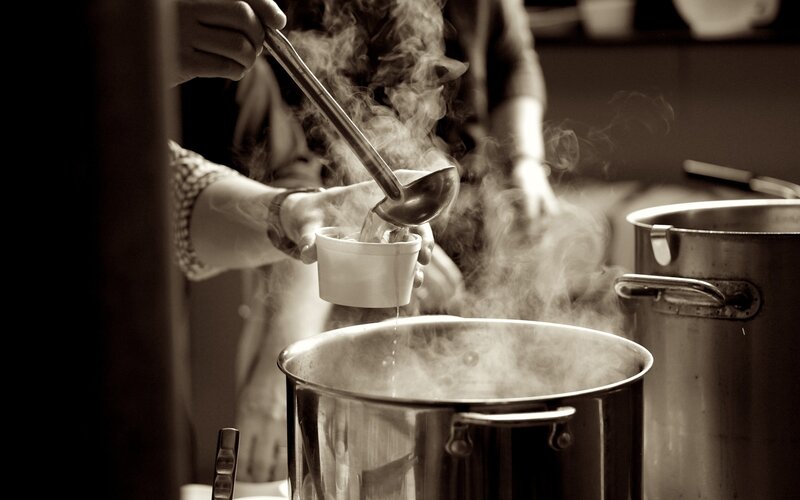 Serving steaming soup from a large pot