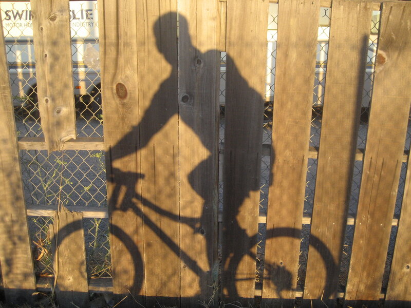 shadow of cyclist on fence