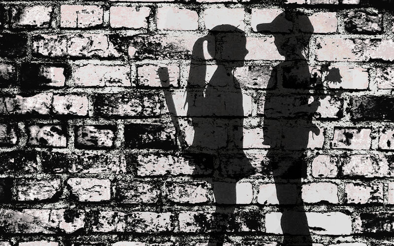 shadows of two figures on brick wall