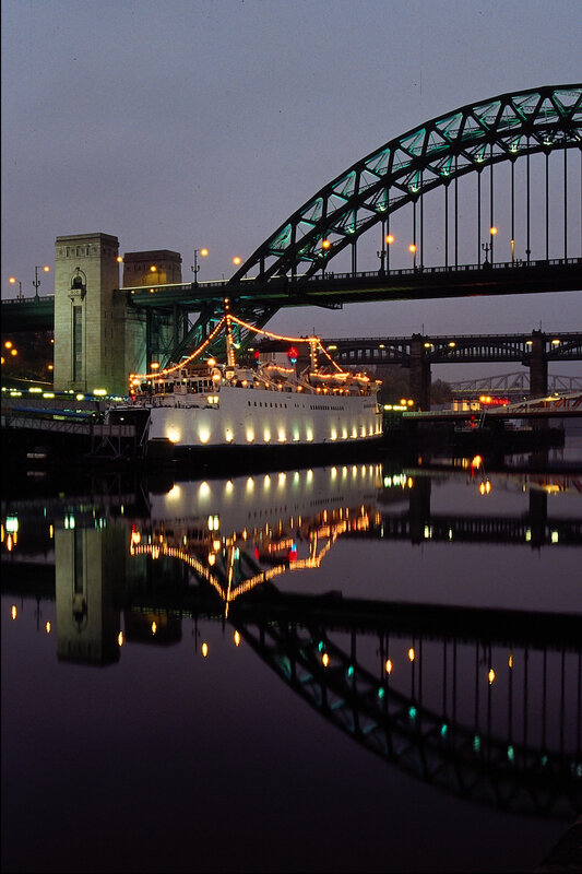 ship under bridge at dusk
