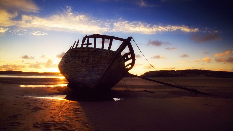 shipwreck at sunset on beach