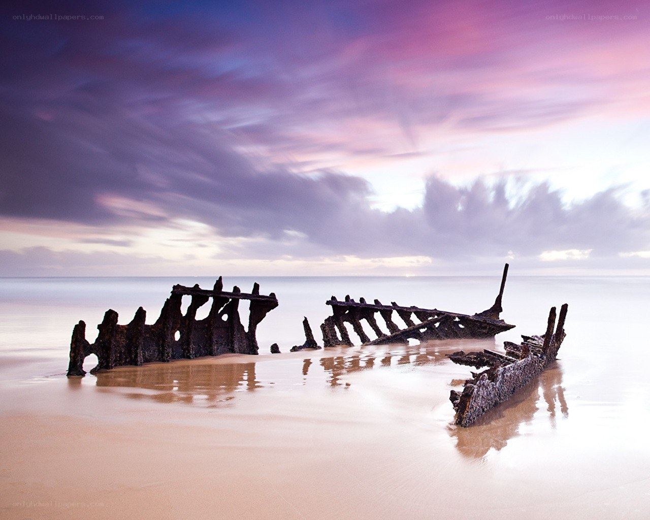 Shipwreck at sunset on beach