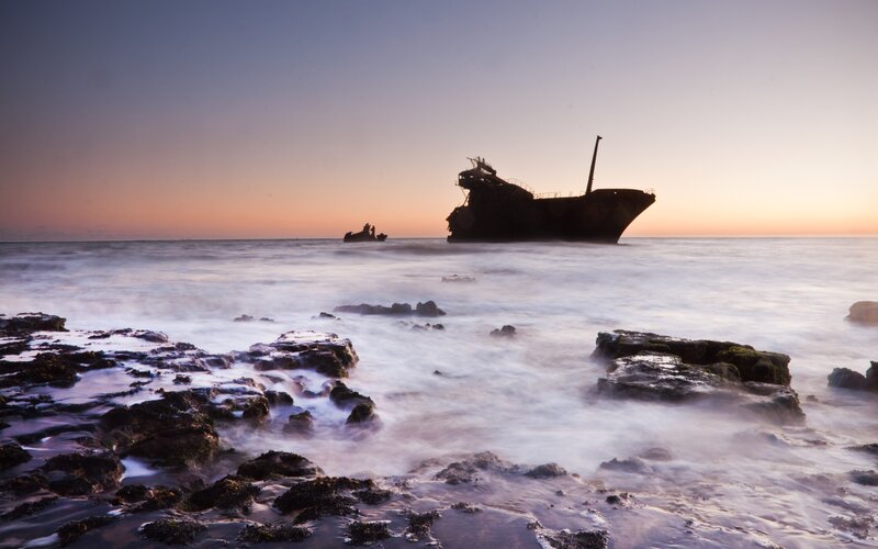 shipwreck at sunset on rocky shore