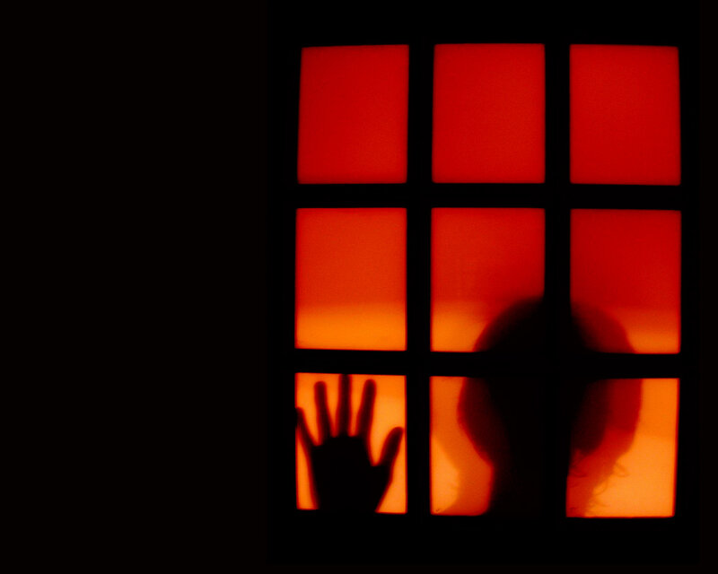 Silhouette at a red-lit window
