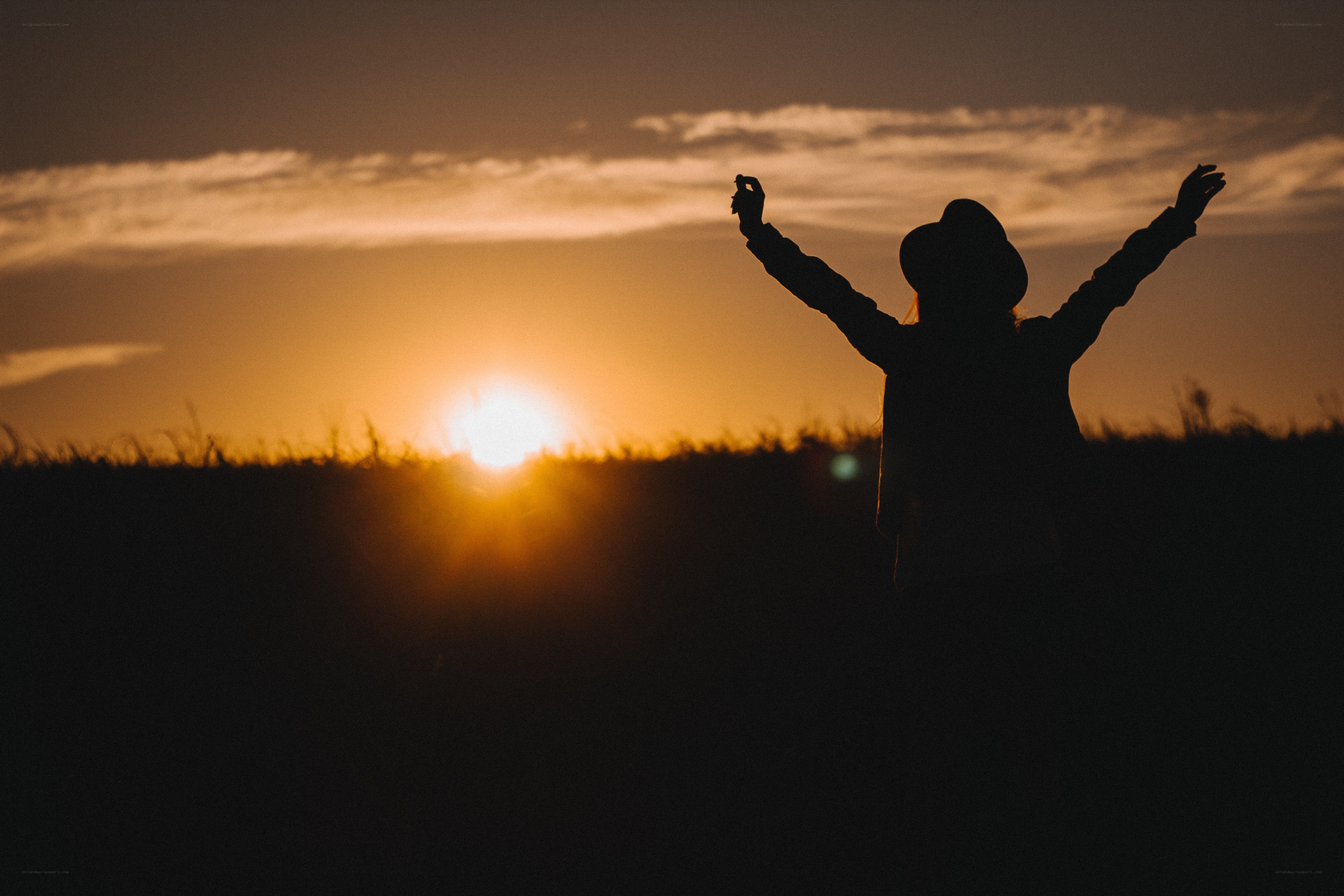 silhouette at sunset with arms raised