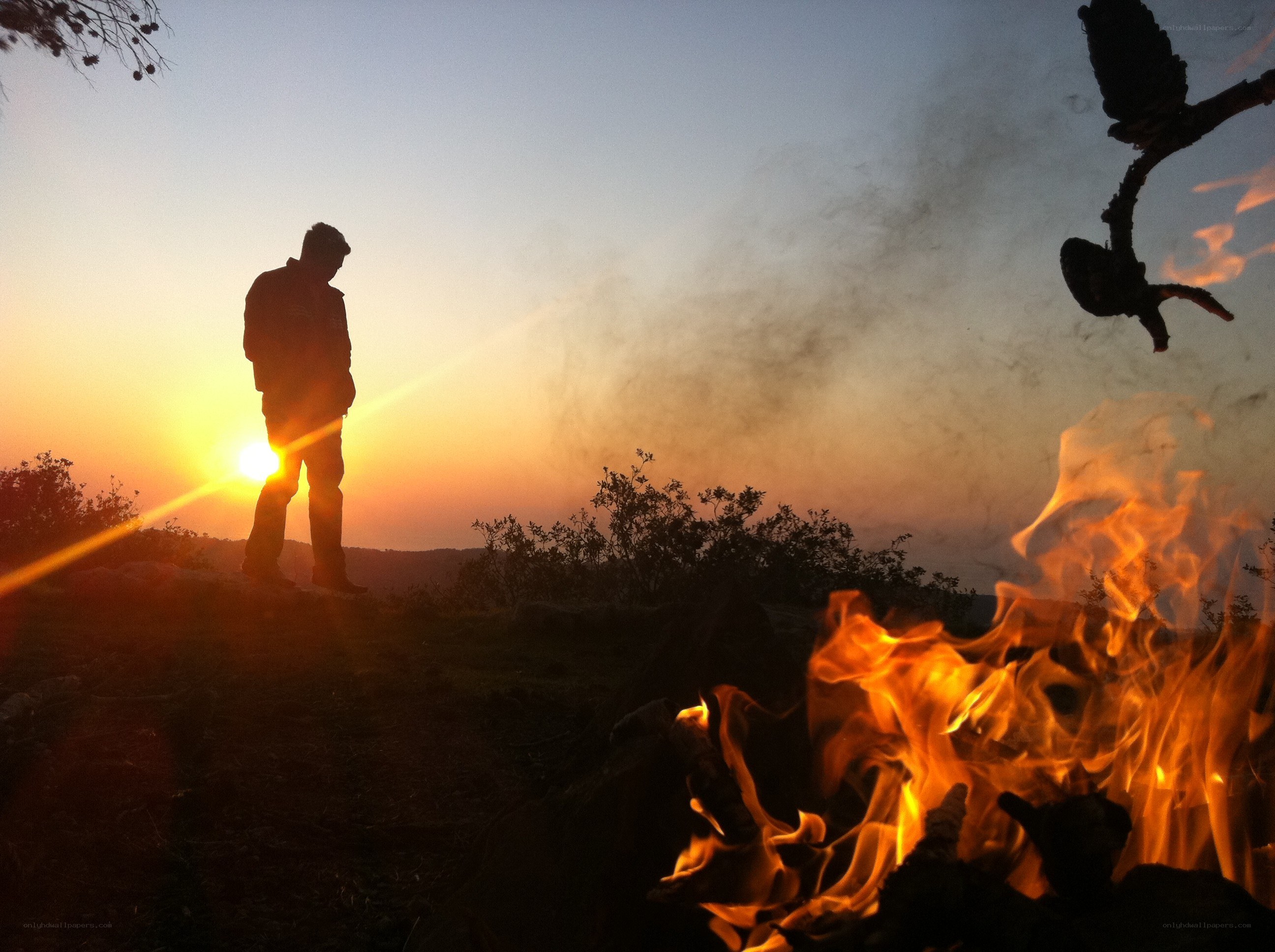 Silhouette at sunset with campfire