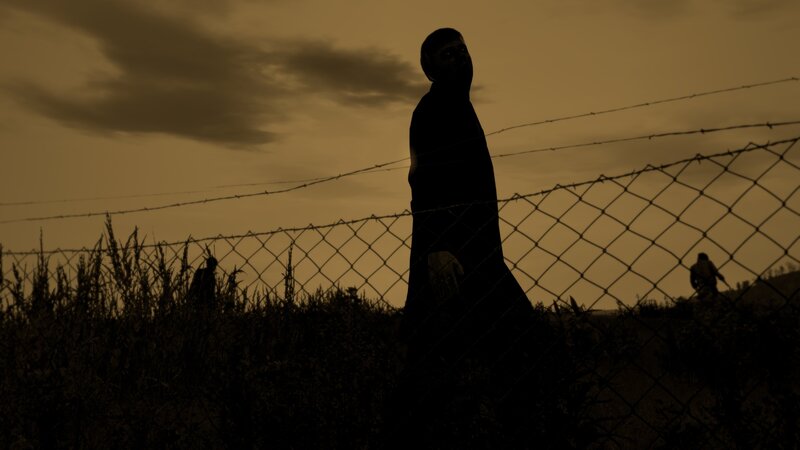 Silhouette behind barbed wire fence
