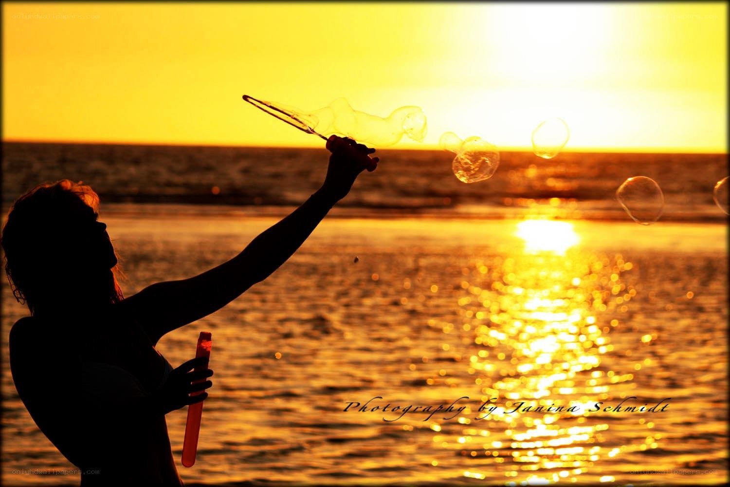 Silhouette blowing bubbles at sunset
