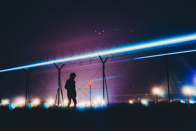 Silhouette by barbed wire fence