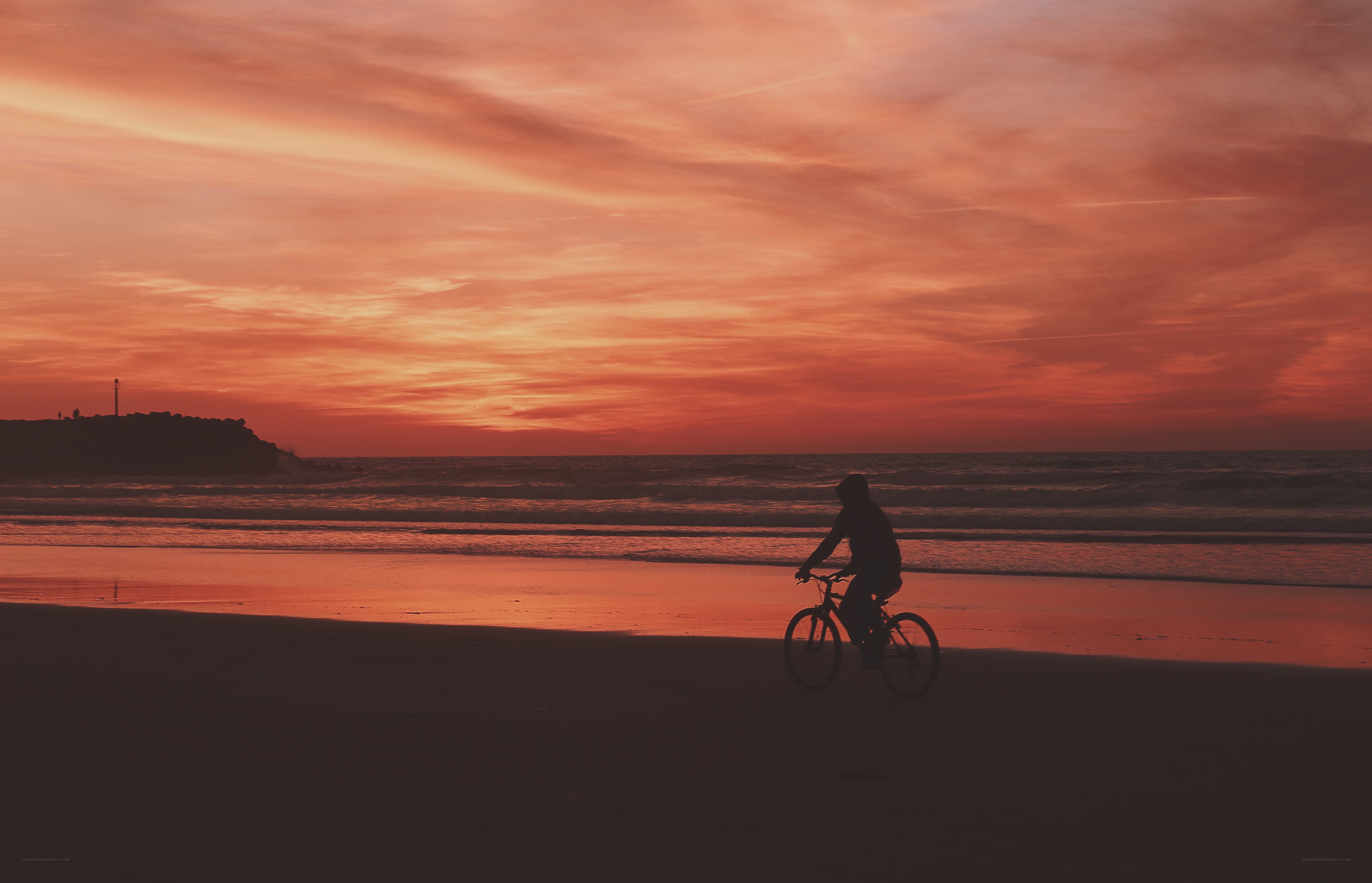 Silhouette cyclist on beach at sunset