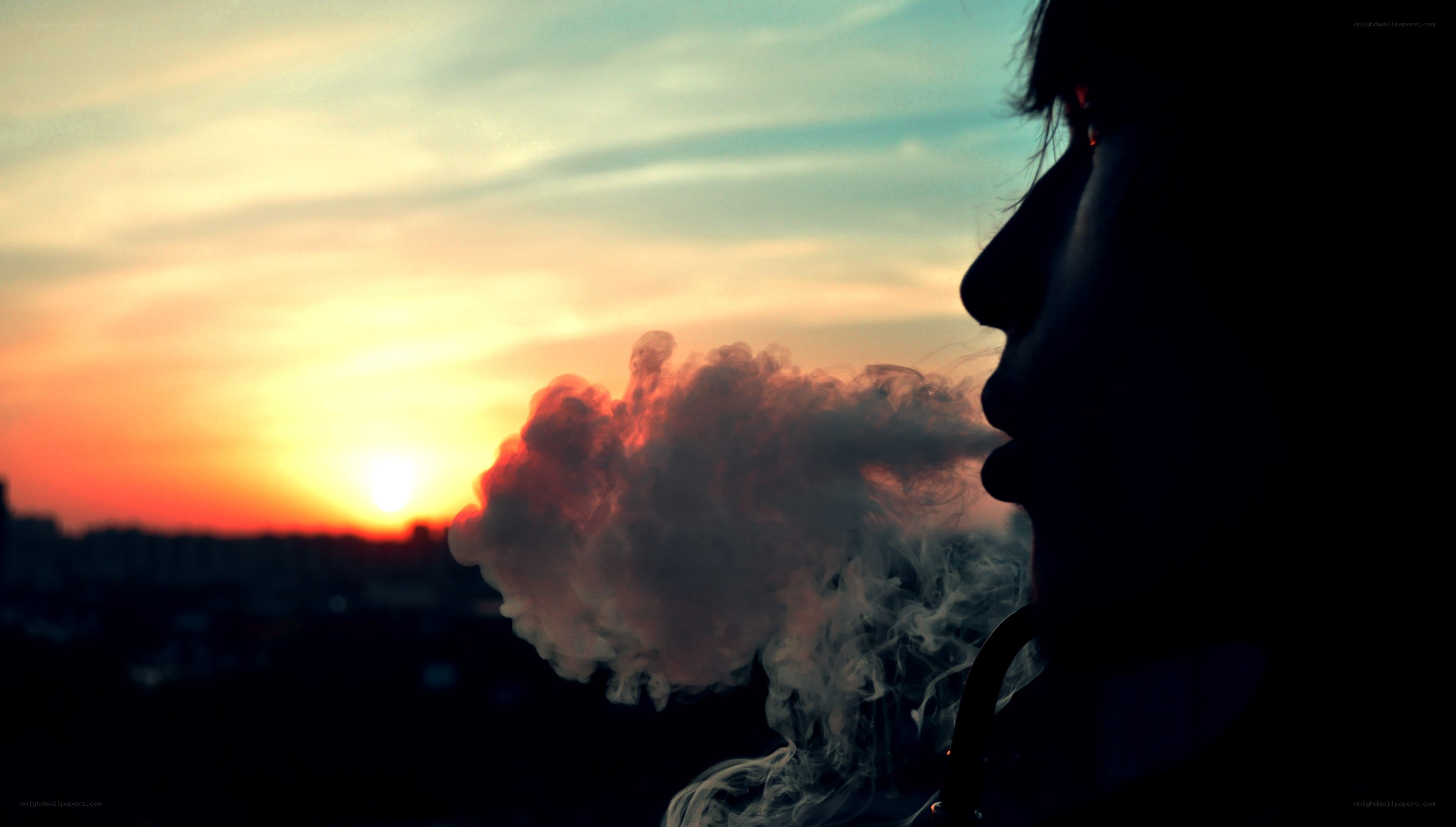 silhouette exhaling smoke at sunset