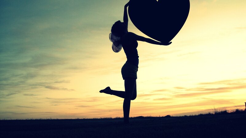 silhouette holding heart at sunset