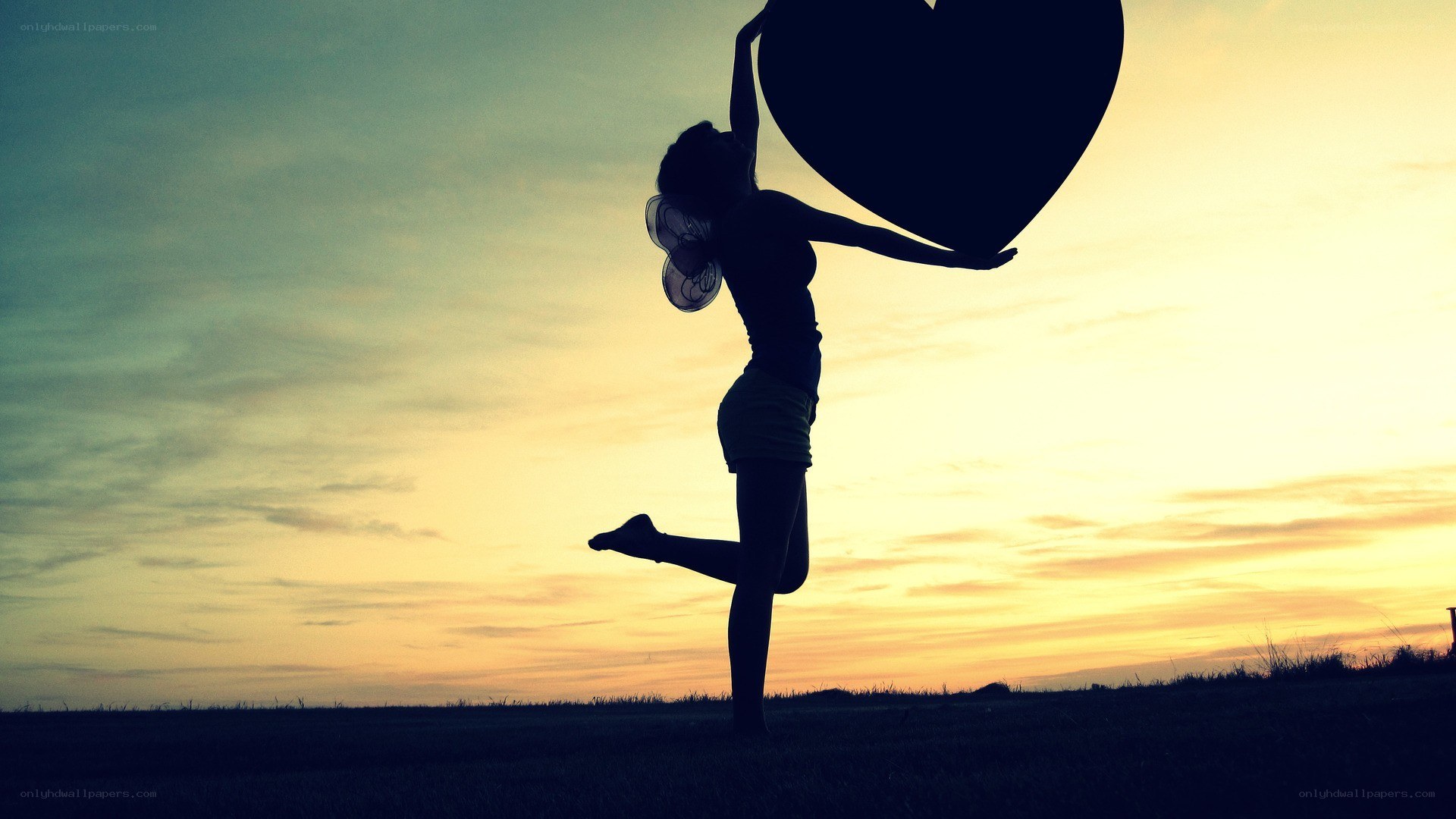 silhouette holding heart at sunset