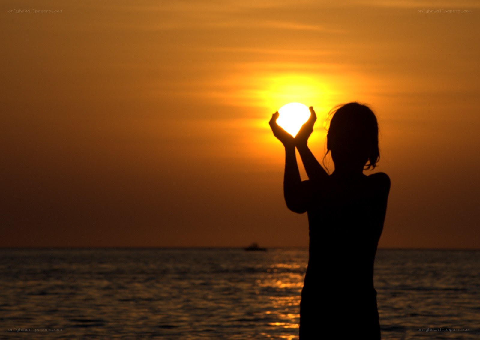 Silhouette holding sun at sunset