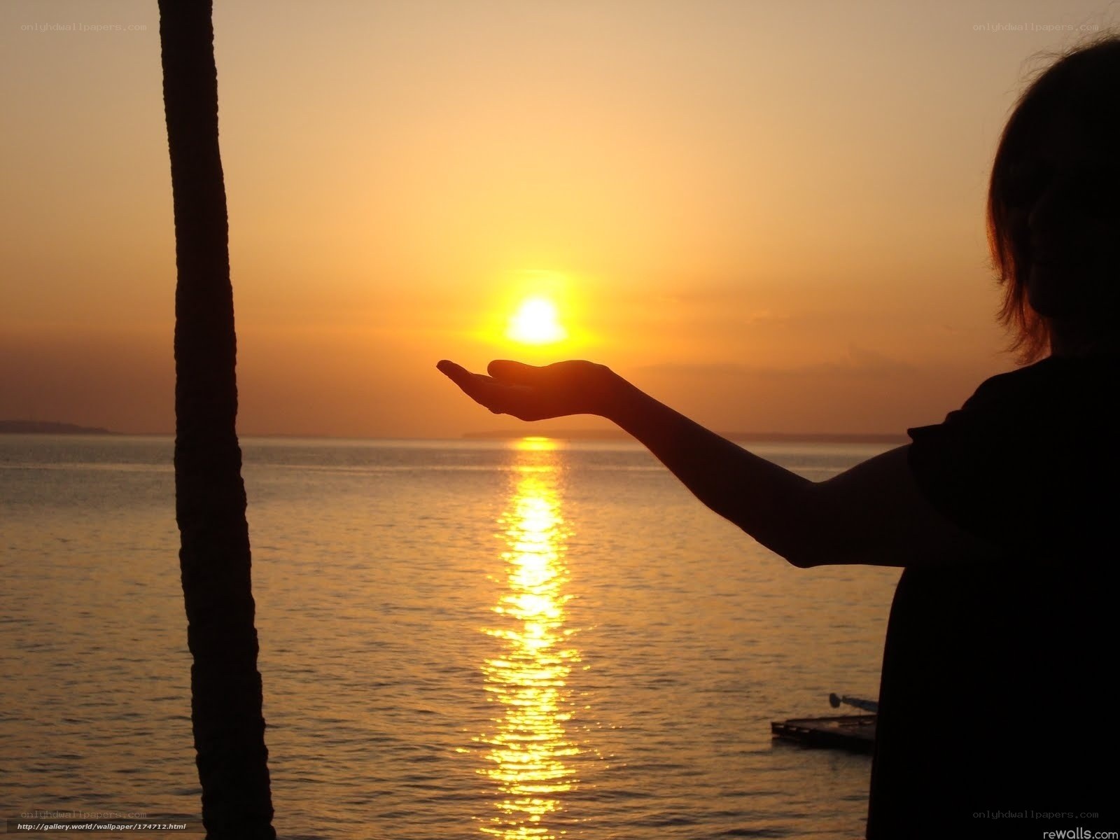 Silhouette holding sun at sunset