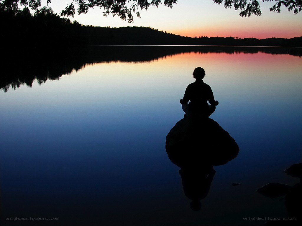 Silhouette meditating by a lake
