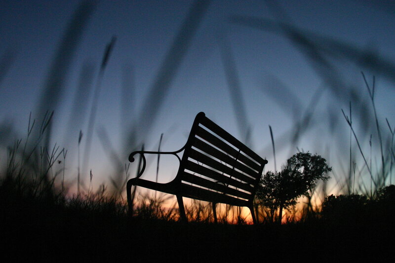 Silhouette of a park bench at dusk