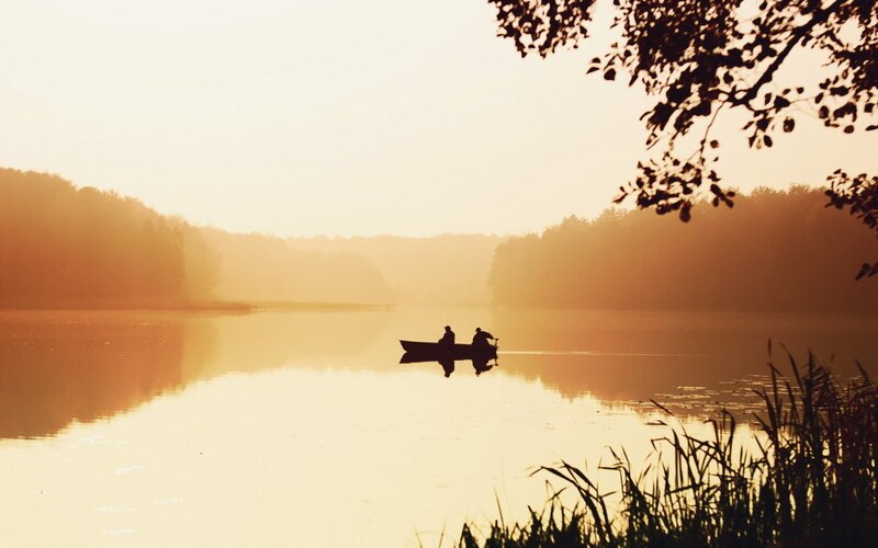 Silhouette of boat on lake at sunrise