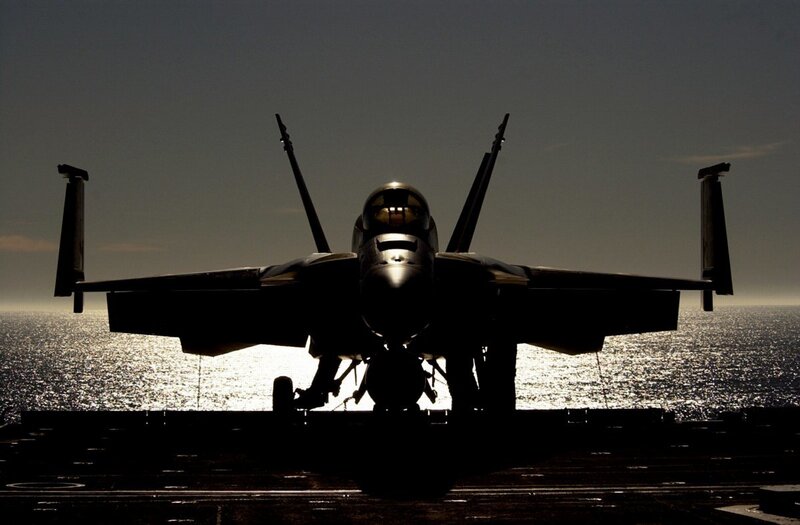 silhouette of fighter jet on aircraft carrier