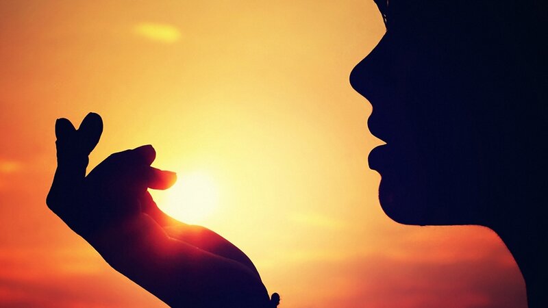 silhouette of hand and face at sunset