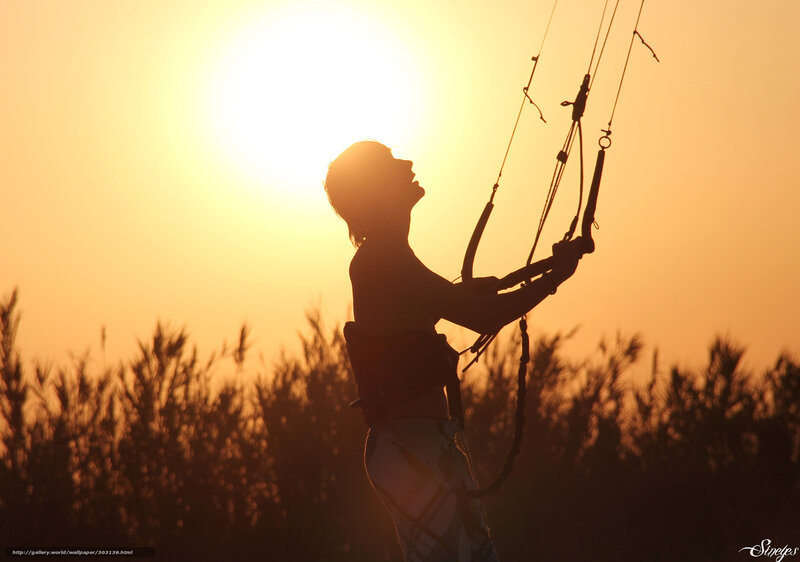 Silhouette of kitesurfer at sunset
