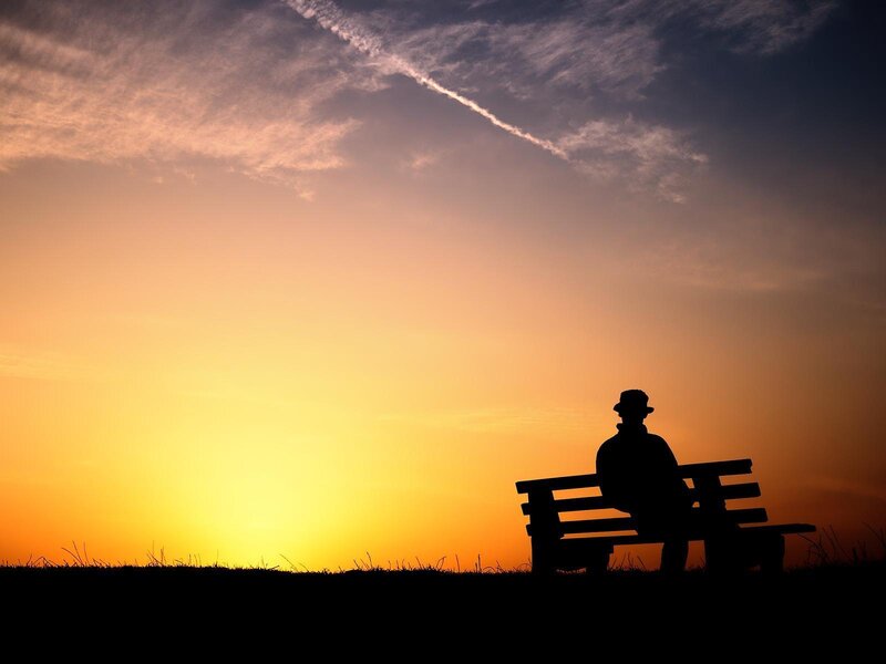 Silhouette of man on bench at sunset
