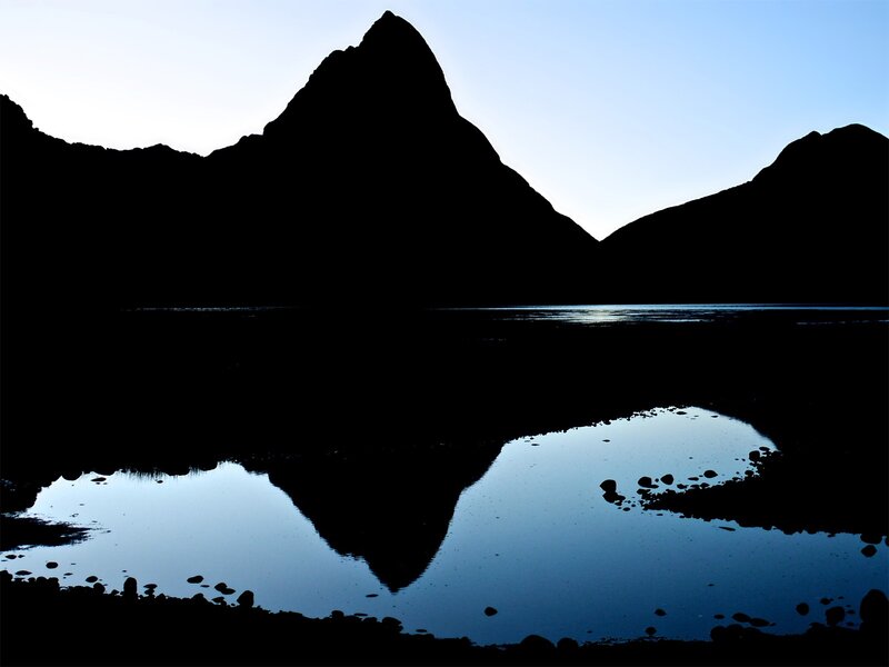 Silhouette of mountain reflected in water