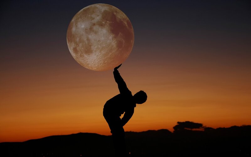 Silhouette of Person Lifting Moon