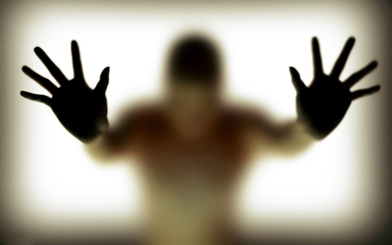 silhouette of person with hands on glass