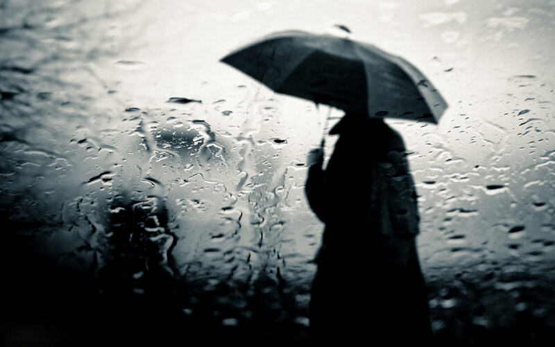 Silhouette of person with umbrella in rain