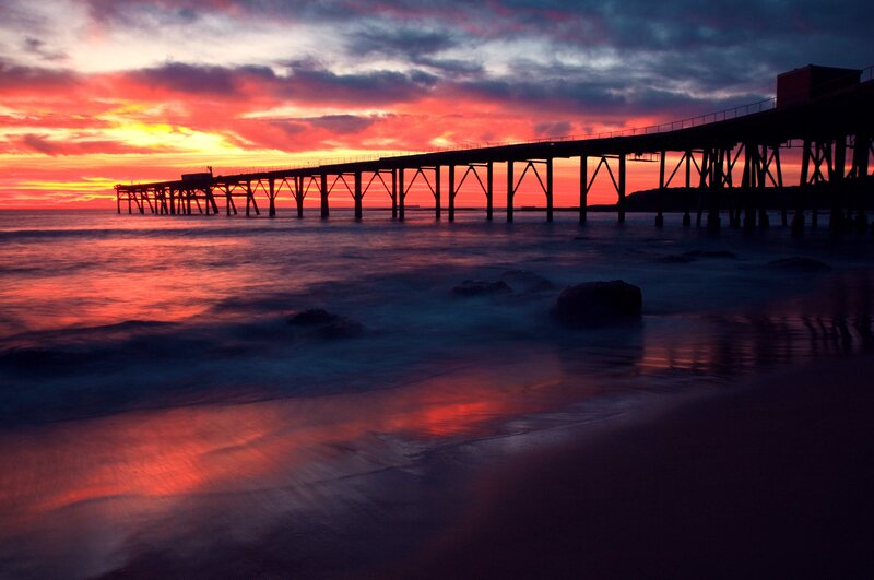 Silhouette of Pier at Sunset — Red, Dramatic, Photograph, Ocean, Sky, Rocks