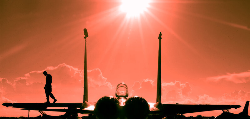 Silhouette of pilot and jet at sunset