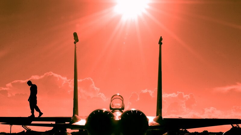 Silhouette of pilot and jet at sunset