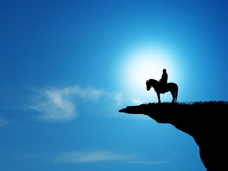 silhouette of rider on cliff