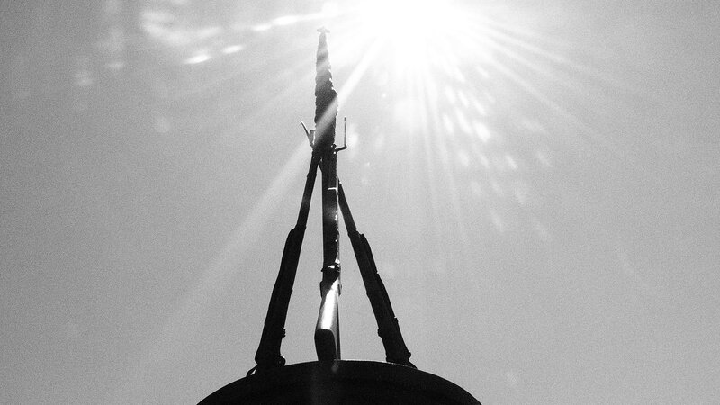 Silhouette of rifles against sun